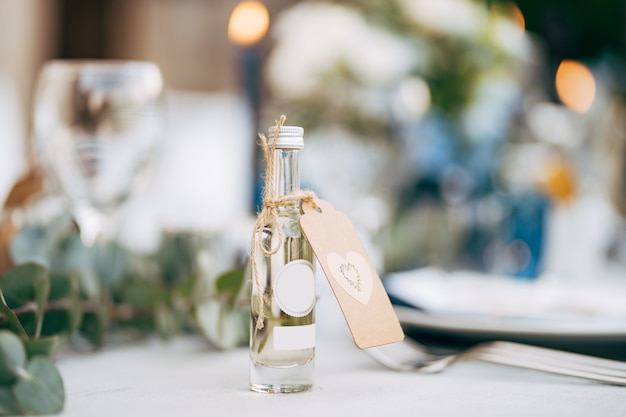 Una piccola bottiglia regalo di alcol sul tavolo del matrimonio