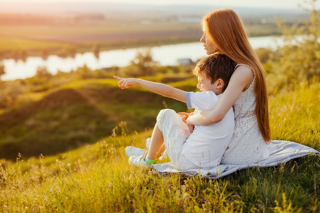 Photo little ginger boy embraced by teen sister pointing finger