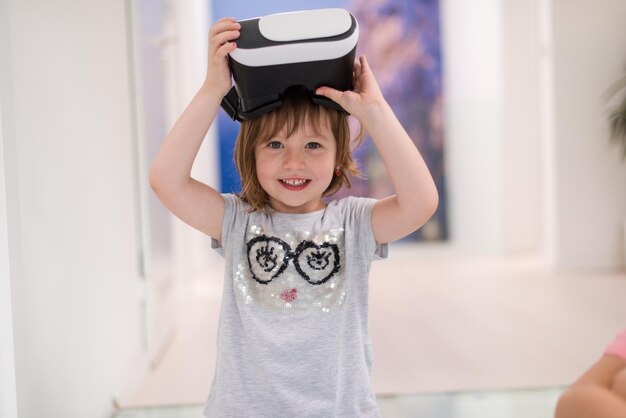 little gir at home wearing vr glasses putting hands up and playing games