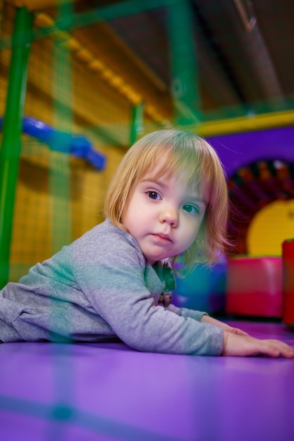 Маленькая девочка 2 лет играет в детской зоне с аттракционами