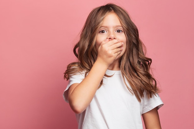 Little girl 7 yerars old on the pink background showing her emotions