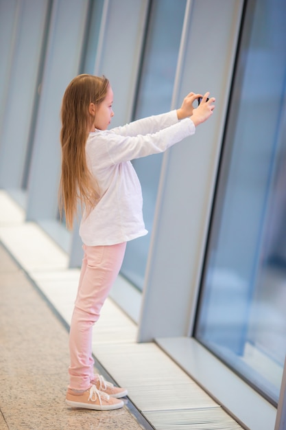 Little girl in airport near big window while wait for boarding