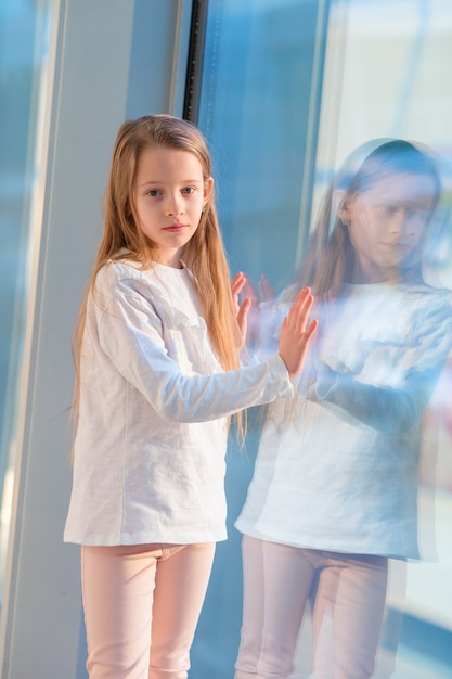 Little girl in airport near big window while wait for boarding