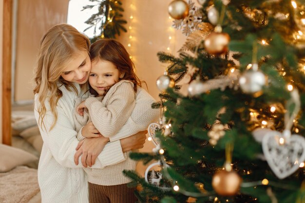 写真 クリスマスツリーの近くで一緒に楽しんでいる小さな女の子と彼女の母親