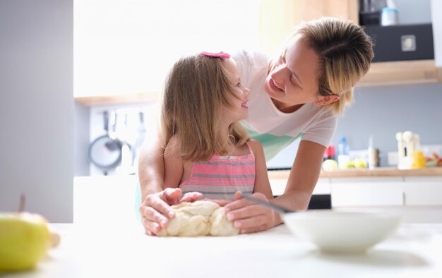 写真 小さな女の子と母親が家でペーストパイを作っている