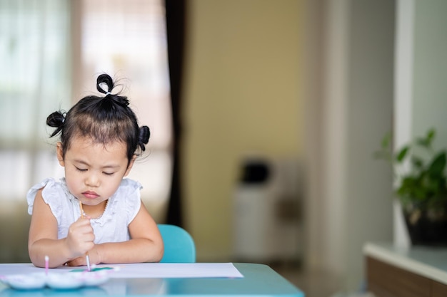 Little girl angry expression face painting on white paper at table