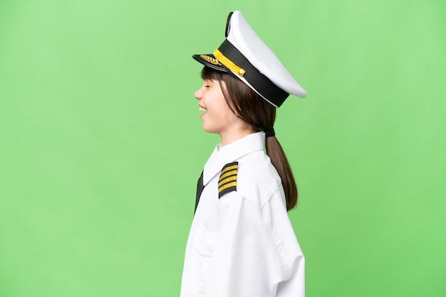 Фото Маленькая девочка в образе пилота самолета на изолированном фоне цветного ключа смеется в боковом положении