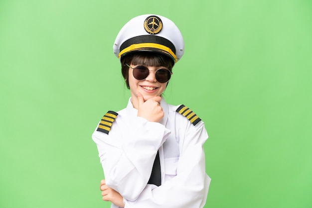 Little girl as a Airplane pilot over isolated chroma key background with glasses and smiling