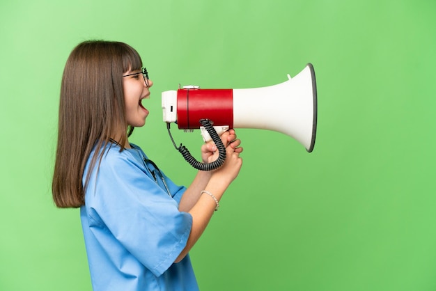 Little girl as a surgeon doctor over isolated chroma key background shouting through a megaphone