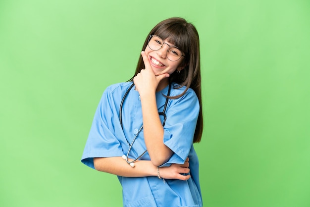 Little girl as a surgeon doctor over isolated chroma key background smiling