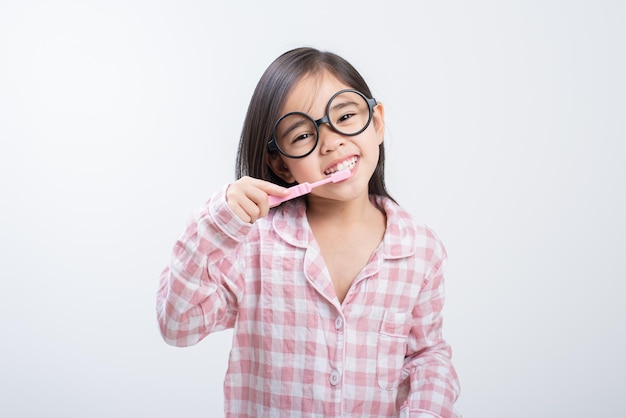 Маленькая девочка Азия чистит зубы счастливо на белом фоне