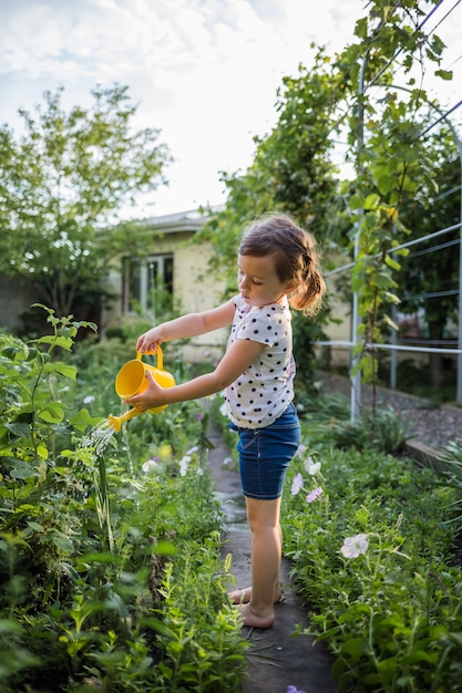 Foto verdure d'innaffiatura dell'assistente della bambina nel giardino