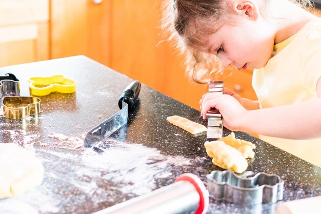 Little girl baking sugar cookies in the kitchen.