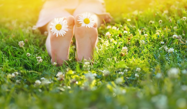 写真 夏の公園の草の上に裸足の女の子が座っている