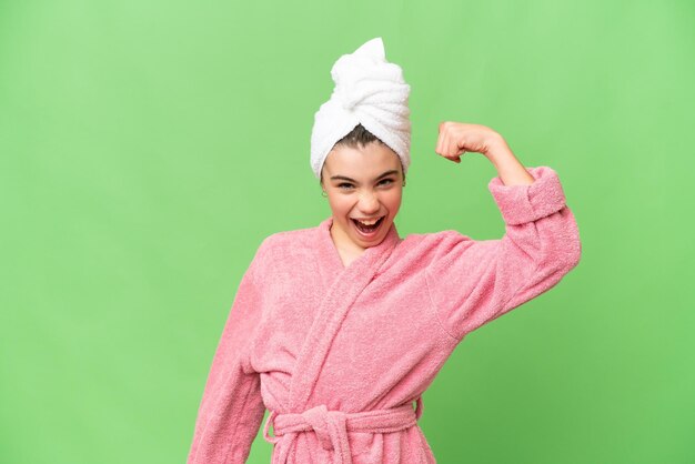 Little girl in a bathrobe over isolated chroma key background doing strong gesture