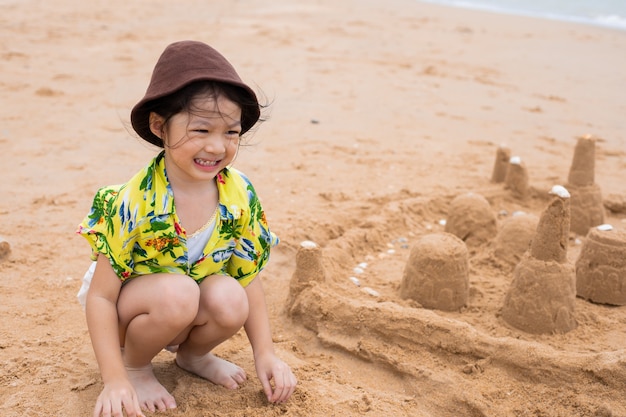 Маленькая девочка на пляже, делая замок из песка