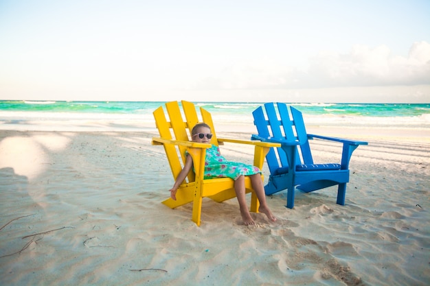 Little girl in beach wooden colorful chairs on tropical Tulum beach, Mexico
