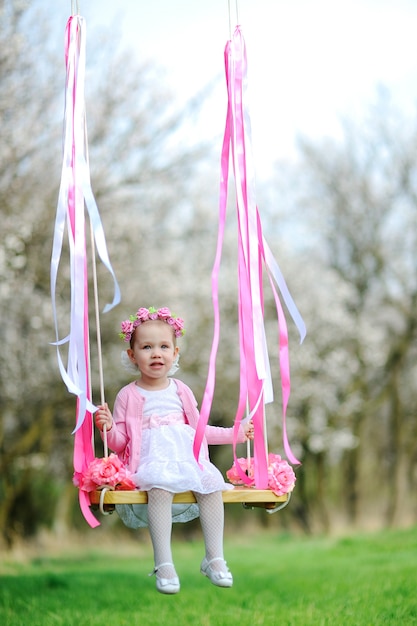 Little girl in a beautiful dress riding on a swing.