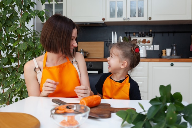 La bambina e la bella mamma stanno cucinando le verdure nella cucina domestica