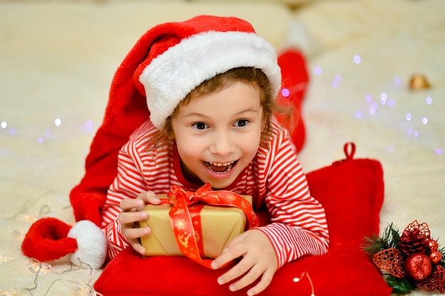 A little girl on the bed with a gift preparation for the celebration new year christmas atmosphere