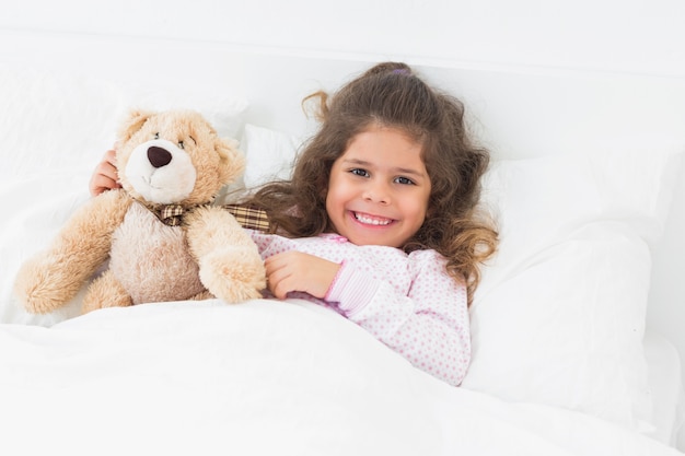 little girl in bed with teddy bear