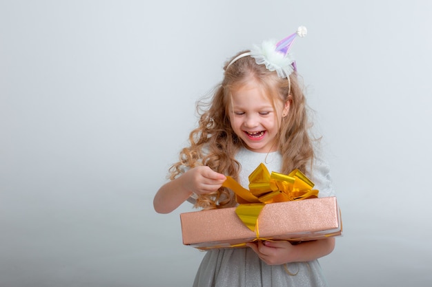 Little girl in a birthday hat holding a gift