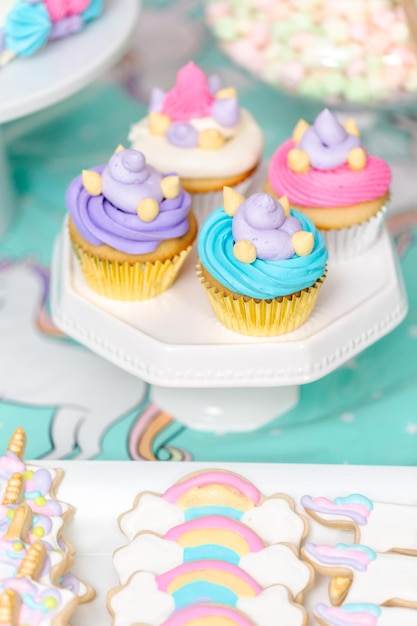 Little girl birthday party table with unicorn cake, cupcakes, and sugaer cookies.