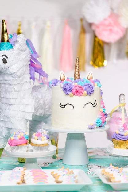 Little girl birthday party table with unicorn cake, cupcakes, and sugaer cookies.