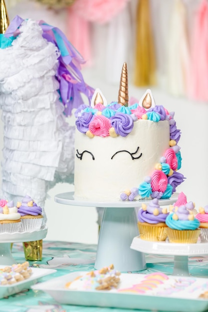 Little girl birthday party table with unicorn cake, cupcakes,\
and sugaer cookies.