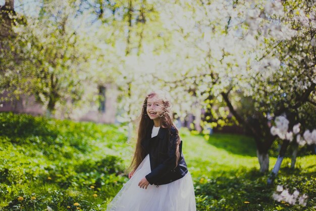 Little girl in black jacket standing and laughing in the spring cherry garden