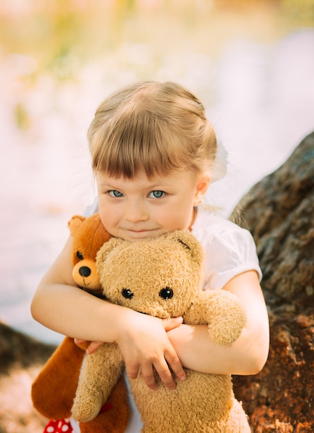 Foto la bionda della bambina abbraccia un orso di peluche. verticale