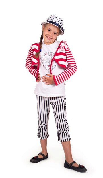 Little girl, blonde in a trendy summer outfit posing in the studio on a white background. In a hat and stylish striped trousers. Shopping concept.