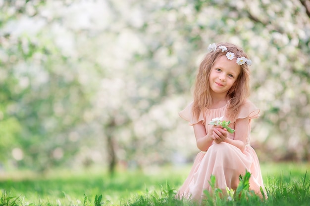 Little girl in blooming cherry tree garden outdoors