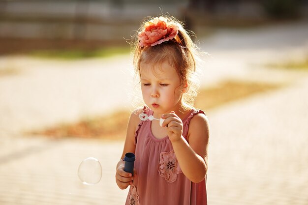 Bambina che soffia bolle di sapone nella sosta di autunno