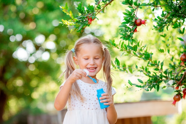 A little girl blows soap bubbles in the park