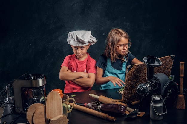 Little girl and boy are cooking vegetables and reading old recipe book.