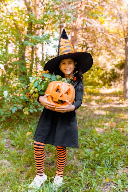 Little girl and boy carving pumpkin at Halloween. Dressed up children trick or treating. Kids trick or treat. Child in witch costume playing in autumn park. Toddler kid with jack-o-lantern.