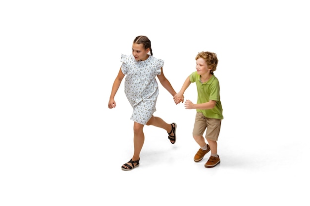 Маленькая девочка и мальчик, бегущие изолированы на белом фоне, счастливы