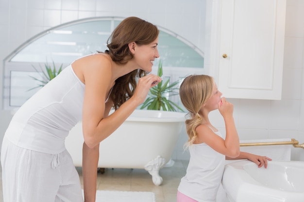 Photo little girl brushing teeth with mother