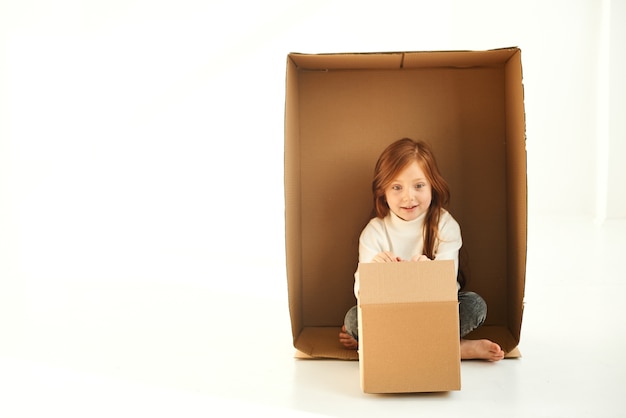 Una bambina in una scatola di cartone nella nuova casa