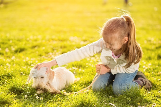 Bambina carezza con il suo cucciolo di cane nel parco