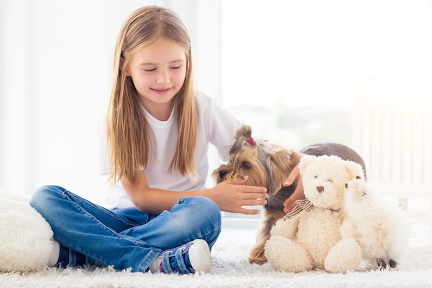 明るい部屋で小さな犬を捕まえる少女