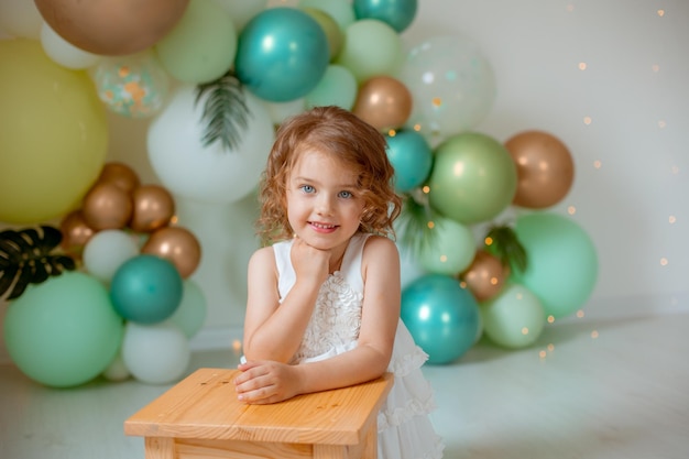 A little girl celebrates her birthday on the background of balloons