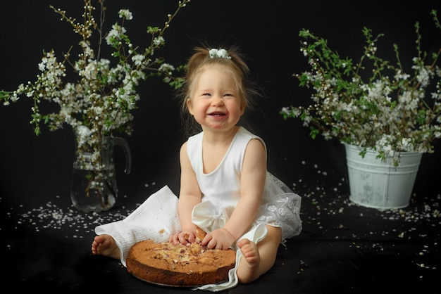 Little girl celebrates her first birthday. Girl eating her first cake.