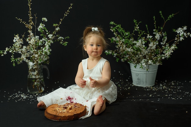 Little girl celebrates her first birthday. Girl eating her first cake.