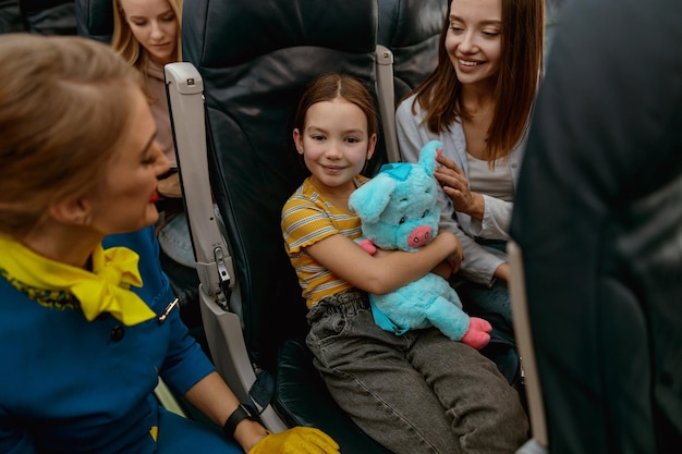 Little girl celebrating birthday with mother and stewardess in plane