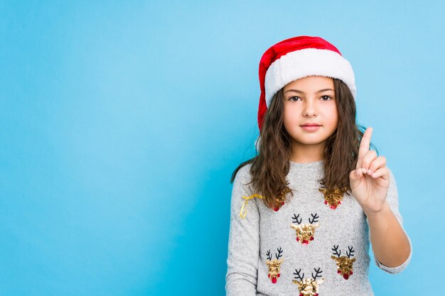 小さな女の子が指でナンバーワンを示すクリスマスの日を祝います。