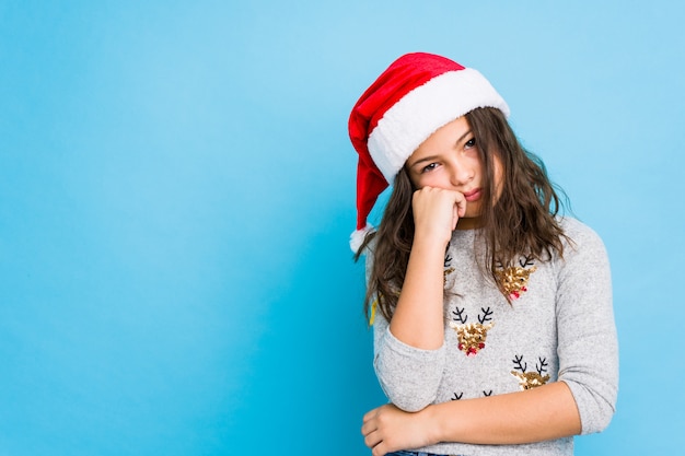 Little girl celebrating christmas day who feels sad and pensive, looking at copy space.