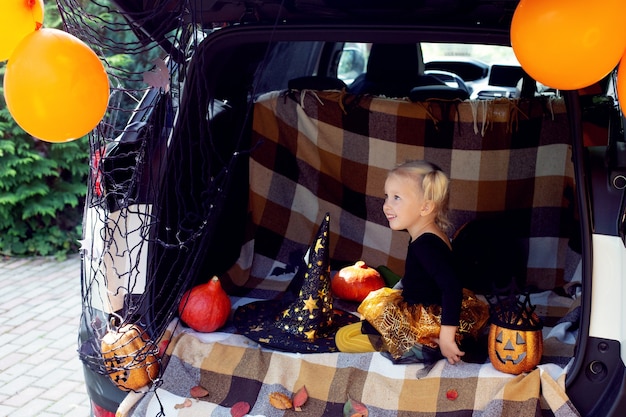 Little girl celebrating halloween car trunk stay home autumn holidays