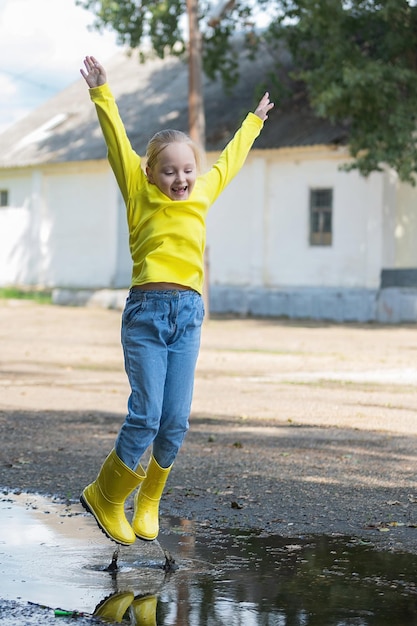 A little girl cheerfully jumps through the puddles in rubber
boots after the rain